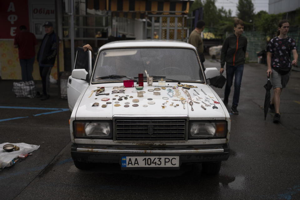 Una amplia variedad de artículos a la venta, expuestos sobre el capó de un Lada 2107, un auto fabricado durante la época soviética, en un mercado callejero en Kiev, Ucrania, el 8 de julio de 2023. (AP Foto/Jae C. Hong)