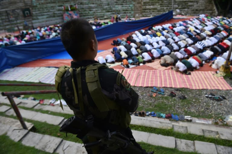 A member of the police special action force stands guard as Muslims, who fled the conflict in Marawi, pray during Eid al-Fitr in Iligan City on the southern island of Mindanao