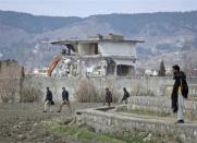 Policemen walk past while demolition work is carried out on the building where al Qaeda leader Osama bin Laden was killed by U.S. special forces last May, in Abbottabad February 26, 2012. Pakistani forces began demolishing the house where al Qaeda leader Osama bin Laden was killed by U.S. special forces, in an unexplained move carried out in the dark of night.