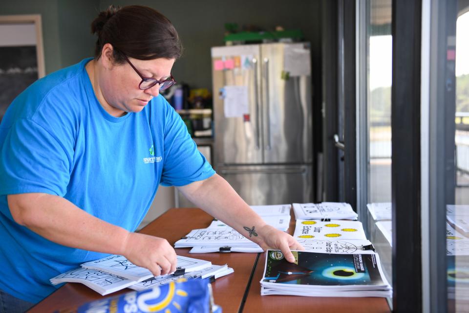 Kristie Oliver, recreation manager at Lake Cooley Outdoor Education Center, sets out solar eclipse activities available to eclipse party attendees before the Partial Eclipse Block Party at the center on Monday, April 8, 2024.