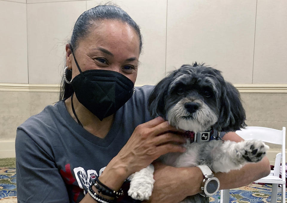 FILE - South Carolina head coach Dawn Staley and her dog Champ pose for a photo, Sunday, Nov. 21, 2021, in Paradise Island, Bahamas, where the team is playing in the Battle 4 Atlantis NCAA college basketball tournament. On Wednesday night, Oct. 12, 2022, Staley will be on the receiving end of more accolades. Staley will accept the Billie Jean King Leadership Award at the Women’s Sports Foundation's Annual Salute to Women in Sports. (AP Photo/Aaron Beard, File)