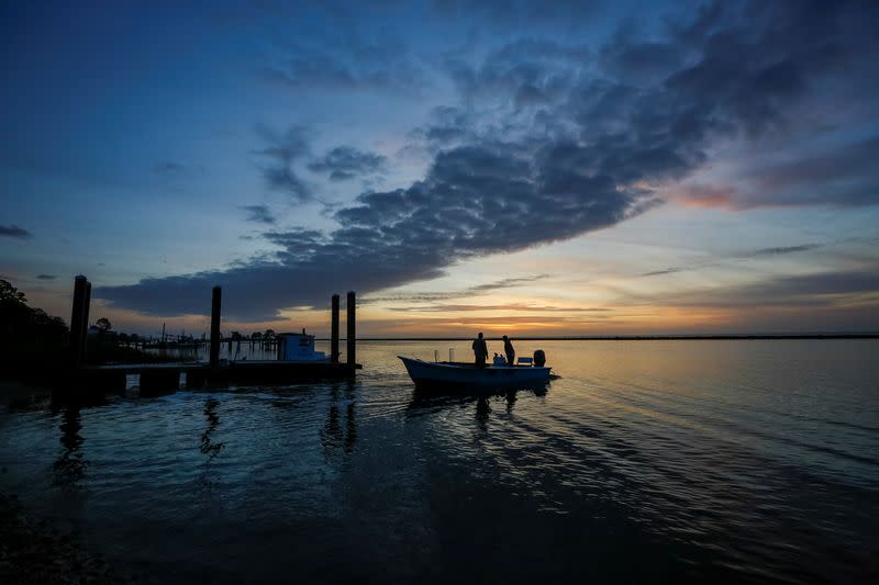 Michael Dasher, Sr., and son Michael Dasher, Jr., both of Eastpoint, Florida, U.S., leave in their boat before dawn for a day of work harvesting oysters from Apalachicola Bay