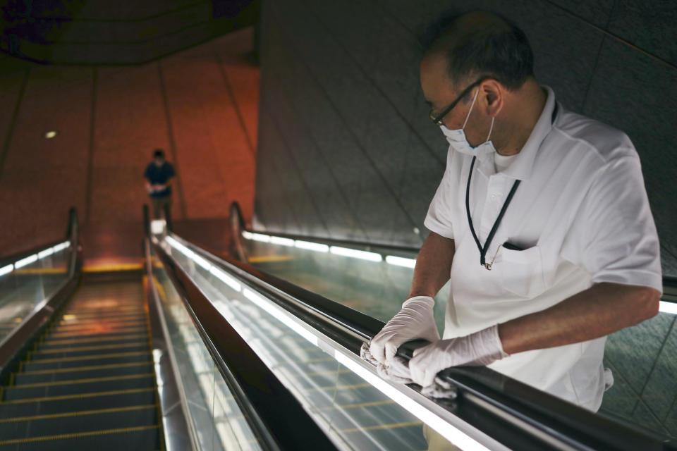 Workers clean the elevators of a business building in Tokyo Tuesday, May 12, 2020. Prime Minister Shinzo Abe has announced that Japan extend a state of emergency until end of May. (AP Photo/Eugene Hoshiko)