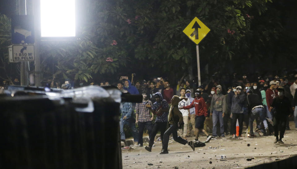 Student protesters throw stones to riot police during a protest outside the parliament in Jakarta, Indonesia Tuesday, Sept. 24, 2019. Police fired tear gas and water cannons Tuesday to disperse thousands of rock-throwing students protesting a new law that they said has crippled Indonesia's anti-corruption agency.(AP Photo/Achmad Ibrahim)