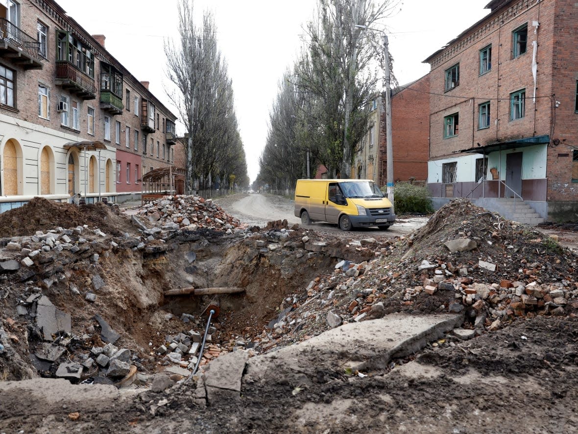 A van drives past a crater in the road caused by a missile strike in the eastern Donbas region of Bakhmut, Ukraine, on Nov. 1.  (Clodagh Kilcoyne/Reuters - image credit)