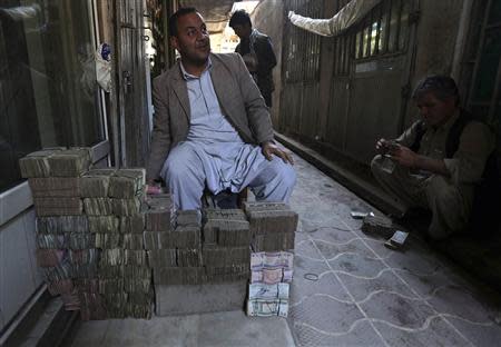 An Afghan money changer sits behind stacks of Afghan currency at Kabul's largest money market April 23, 2014. REUTERS/Omar Sobhani