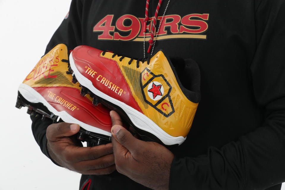 Earl Mitchell holds his custom made "Connor's Cure" cleats — San Francisco 49ers