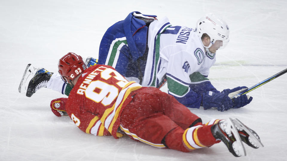 Vancouver Canucks' Elias Pettersson, right, collides with Calgary Flames' Sam Bennett during the second period of an NHL hockey game Saturday, Jan. 16, 2021, in Calgary, Alberta. (Jeff McIntosh/The Canadian Press via AP)