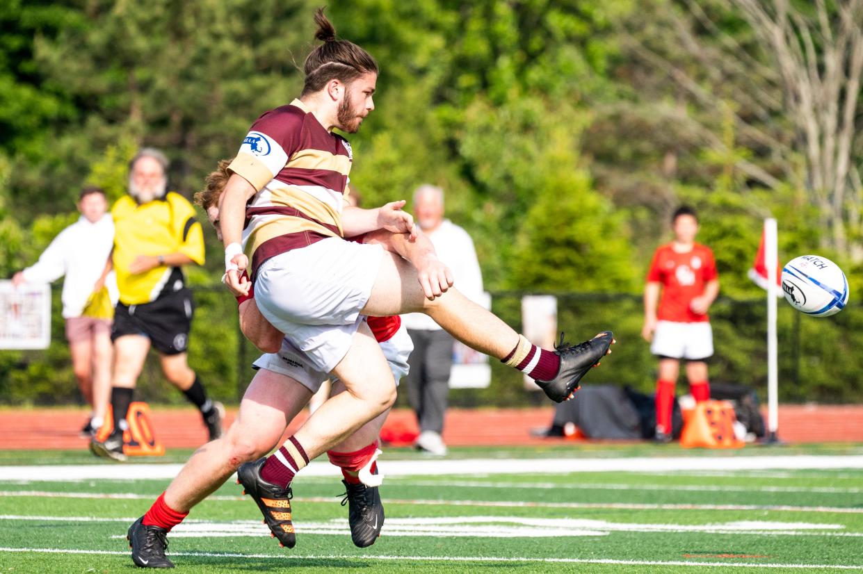 Algonquin's Nick Southey kicks the ball as he is tackled In the Division 2 state semifinals in Westborough, June 8, 2023.