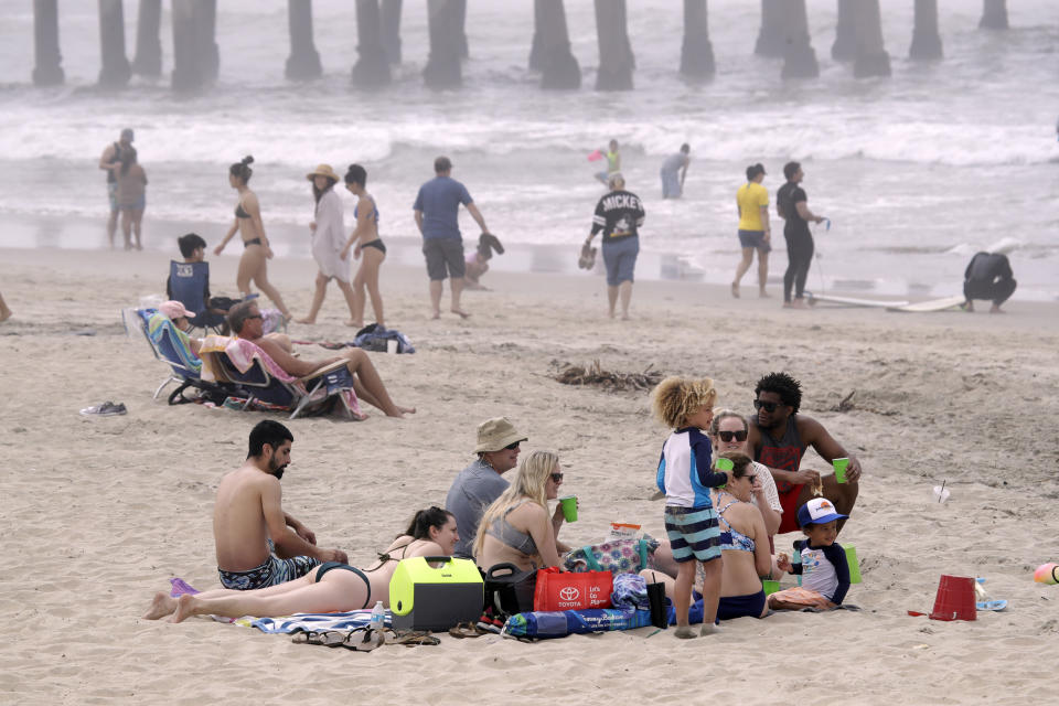 FILE - In this April 26, 2020, file photo, people sit on the beach in Huntington Beach, Calif. A memo sent to California police chiefs says Gov. Gavin Newsom will order all beaches and state parks closed starting Friday, May 1, to curb the spread of the coronavirus. The California Police Chiefs Association sent the bulletin to its members Wednesday evening. Association President Eric Nuñez said it was sent to give chiefs time to plan ahead of Newsom’s expected announcement Thursday. (AP Photo/Marcio Jose Sanchez, File)