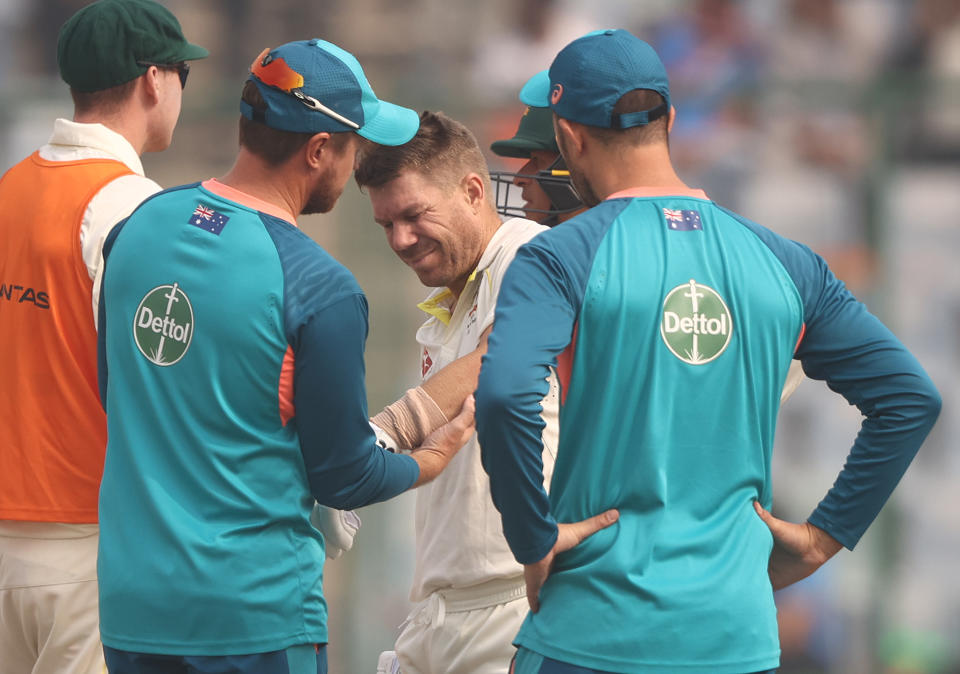 David Warner (pictured middle) in pain after hurting his elbow.