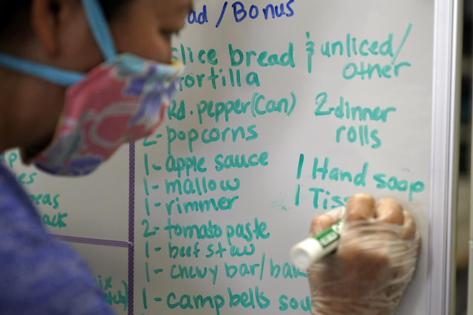 Cheryl Mah lists available items at Porchlight Community Service food pantry Thursday, May 6, 2021, in San Diego. For millions of Americans with food allergies or intolerances, the pandemic has created a particular crisis: Most food banks and government programs offer limited options. (AP Photo/Gregory Bull)