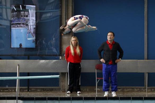 A member of Crystal Palace diving club dives watched by head coach Chen Wen (R) during a training session in London March 9, 2012.