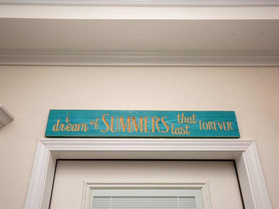 A sign that reads "I dream of summers that last forever." above a doorway.