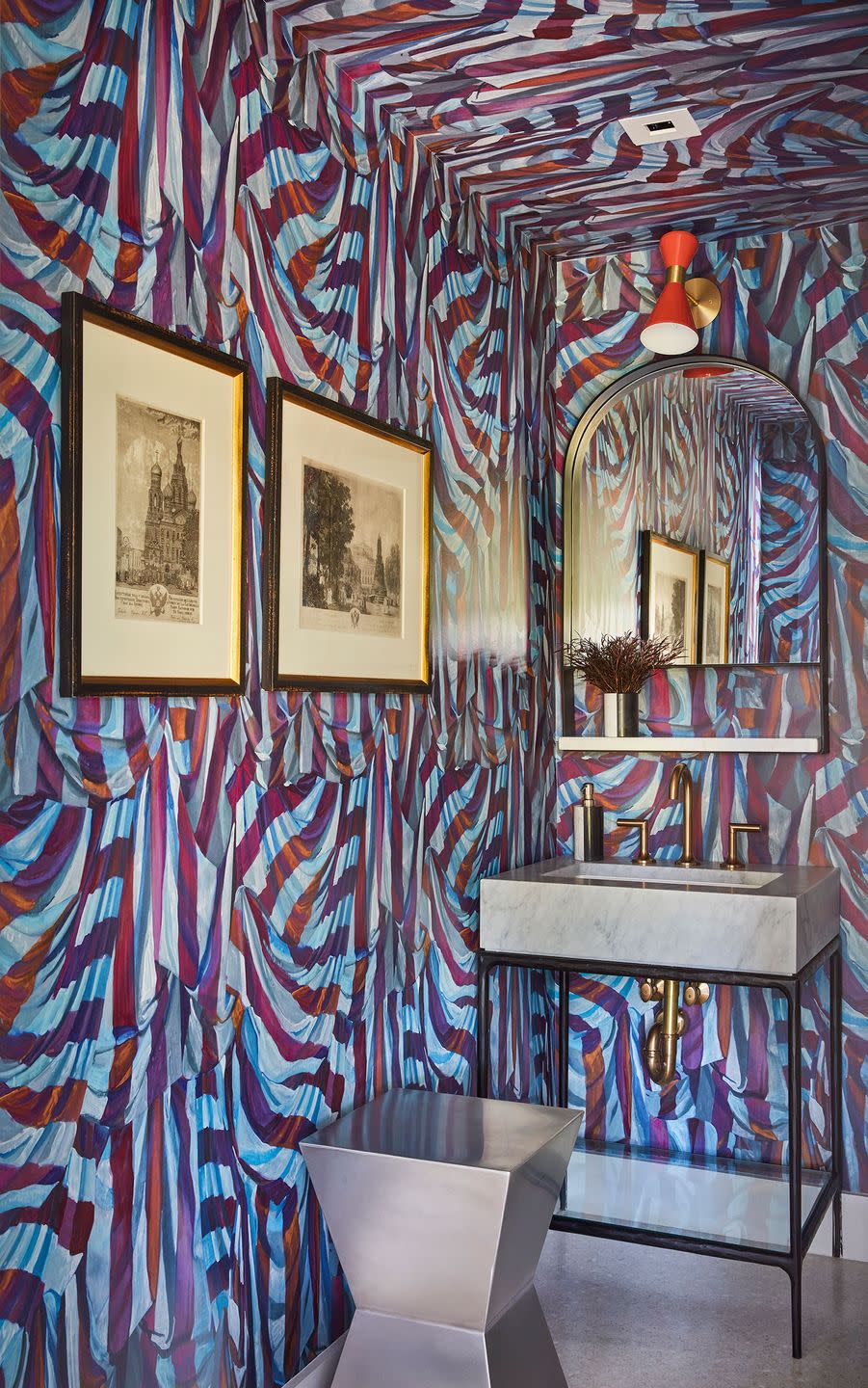 small powder room with metal sink and a wallpaper that looks like draperies in reddish blue tones