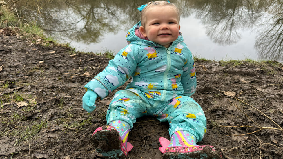 Esmee sitting down in a blue rain suit