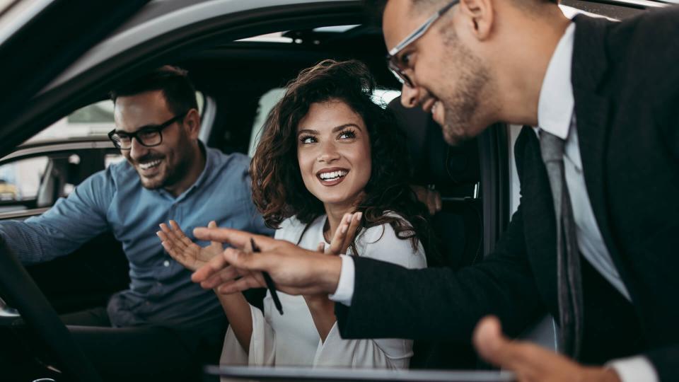 Middle age couple choosing and buying car at car showroom.