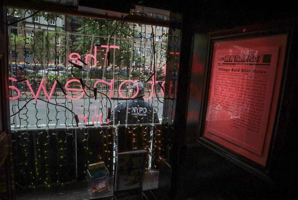 In this Friday, June 14, 2019, photo, a framed newspaper clipping hangs inside the Stonewall Inn, covering the 1969 riots that followed a police raid of the bar in New York. Some of the news coverage of rioting outside the bar was a source fury that led Stonewall to become a synonym for the fight for gay rights. (AP Photo/Bebeto Matthews)