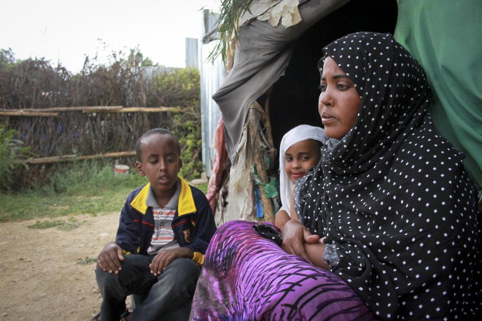 In this photo taken Sunday, April 27, 2014, Ubah Mohammed Abdule, 33, right, sits with her son Abdullahi Yusuf Ahmed, 8, left, and daughter Neshad Yusuf Ahmed, 5, center, outside her hut in the Shedder refugee camp near the town of Jigjiga, in far eastern Ethiopia. The Somali mother’s home is a small shelter with a frame of sticks covered by ragged blankets on the dusty grounds of a refugee camp but it was to her that her 15-year-old son Yahya Abdi wanted to travel to on an impossible journey as a stowaway on a plane from California. (AP Photo/Elias Asmare)