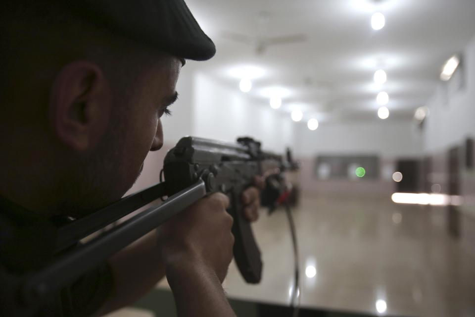 Palestinian security officer Ahed Abu Shabban, 23, fires an an electronically-modified AK-47 rifle at the headquarters of the security training department of the Hamas interior ministry in Gaza City, in the northern Gaza Strip on Thursday, April 10, 2014. The laser-fitted rifles are a money saver that eliminates the need to train with live ammunition, which is in short supply in Gaza. (AP Photo/Adel Hana)