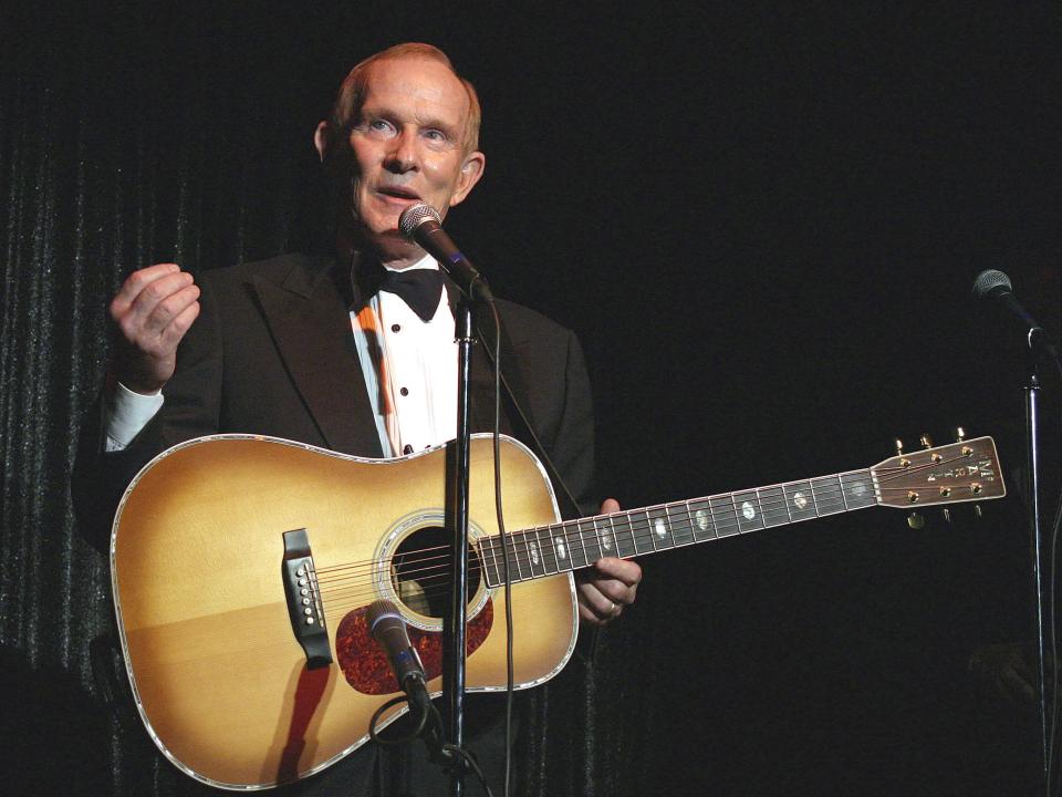 Tom Smothers in a tuxedo holding a guitar