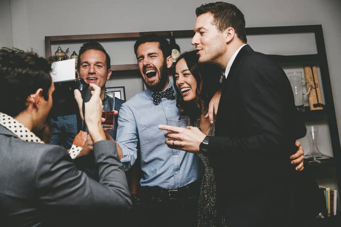 A group of friends sharing a joyful moment while posing for a photo at an indoor gathering