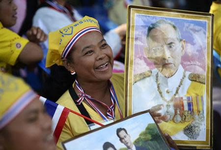 An anti-government protester holds a poster of Thai King Bhumibol Adulyadej to celebrate his 86th birthday in Bangkok December 5, 2013. REUTERS/Dylan Martinez