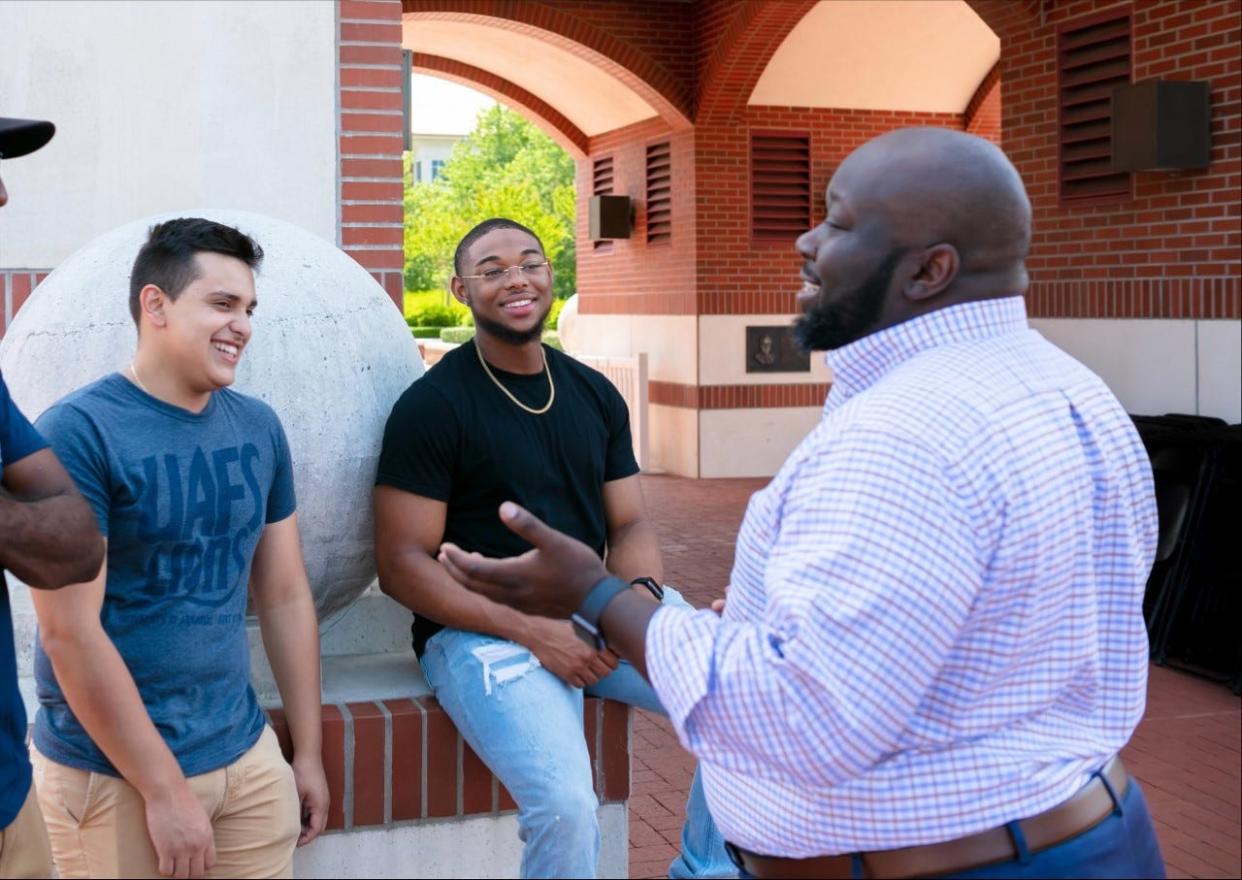 Matthew Bonilla and Glenn Brewer II, the Men of Excellence president, speak with John Blue (right), executive director of diversity equity and inclusion.