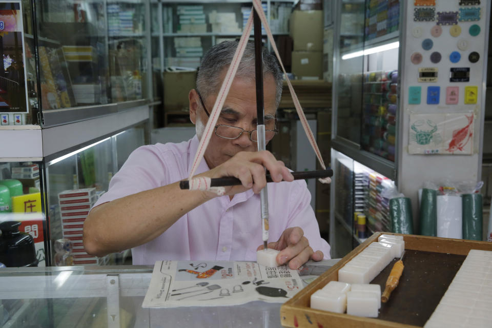 In this April 18, 2019, photo, Cheung Shun-king, 65-year-old mahjong game tiles maker, engraves a character on a tile in his shop in Kowloon's old neighborhood of Hong Kong. (AP Photo/Kin Cheung)