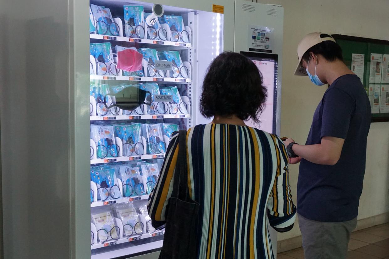 Residents get free reusable face masks from a vending machine by scanning their identification card, set up by the government as part of the effort to halt the spread of the COVID-19 coronavirus, at a community centre in Singapore on May 28, 2020. (Photo by ROSLAN RAHMAN / AFP) (Photo by ROSLAN RAHMAN/AFP via Getty Images)