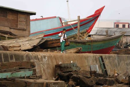 A boy walks along the sea wall in Muara Baru, north Jakarta, October 7, 2014. Picture taken October 7, 2014. REUTERS/Darren Whiteside