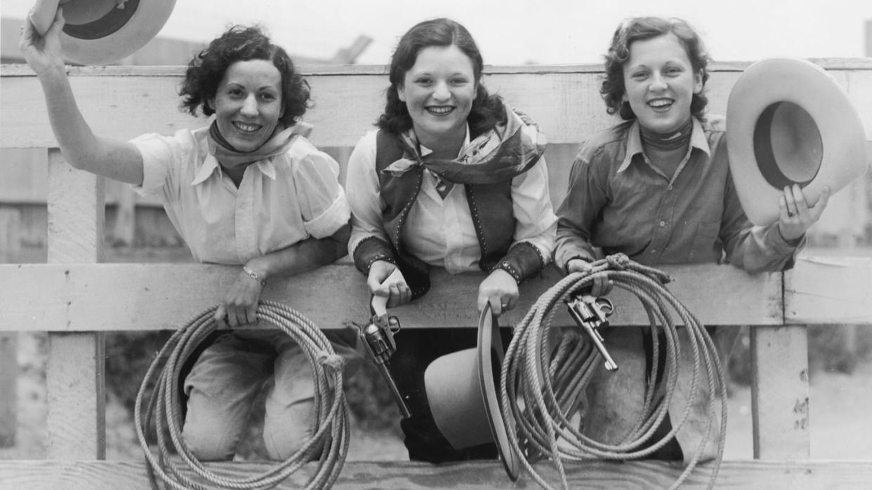 three cowgirls on a fence