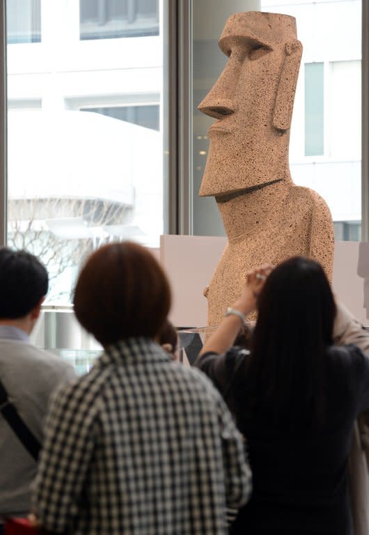 Visitors look at the new "Moai" statue as it is unveiled in Tokyo, on March 20, 2013. The statue is modelled on the mysterious carvings at Easter Island, and was presented to the tsunami-devastated town of Minamisanriku after the town's original statue was destroyed in the March 2011 quake and tsunamis