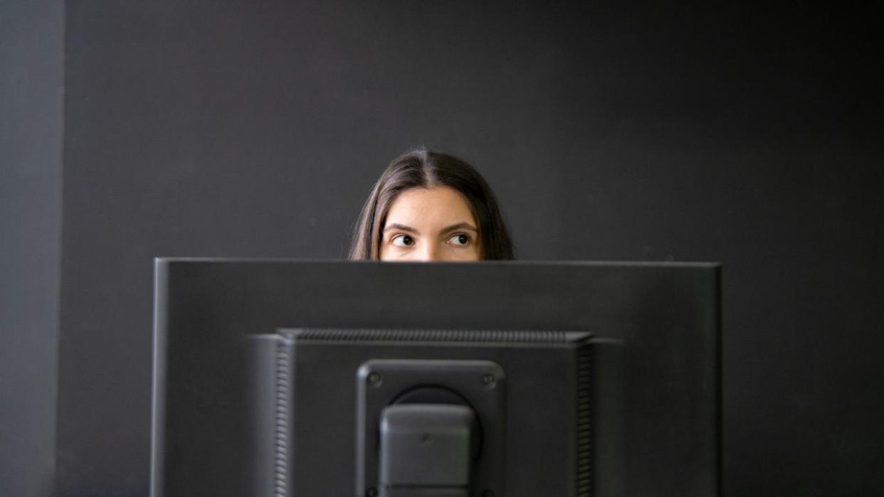 worker peeking from behind computer