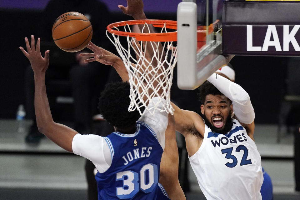 Minnesota Timberwolves center Karl-Anthony Towns, right, passes the ball as Los Angeles Lakers center Damian Jones defends during the first half of an NBA basketball game Tuesday, March 16, 2021, in Los Angeles. (AP Photo/Mark J. Terrill)