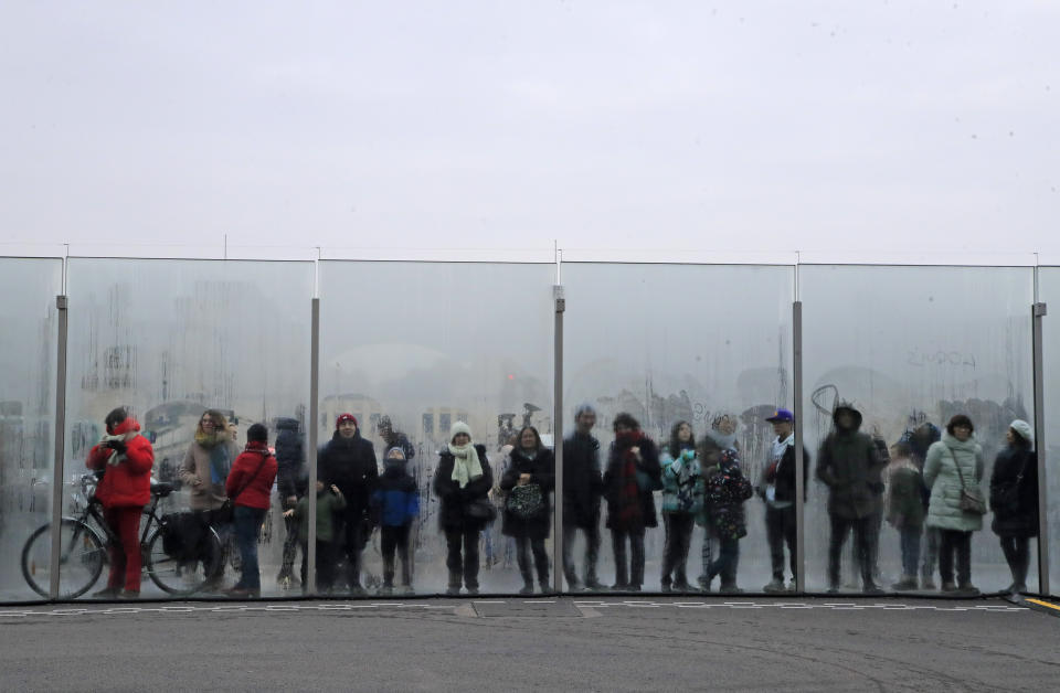 People watch through the security bulletproof glass barrier at the Eiffel Tower in Paris, Saturday Jan. 25, 2020, the dance performance who marks the Chinese New Year. This year marks the "Year of the Rat" in the Chinese Lunar calendar. (AP Photo/Michel Euler)