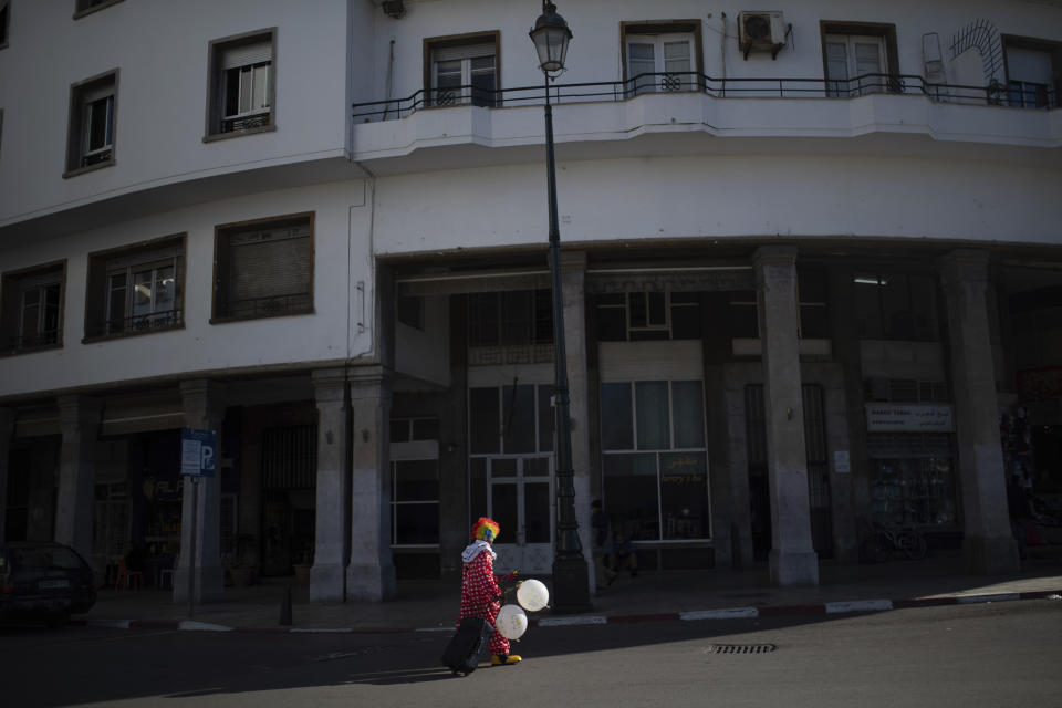 Belhussein Abdelsalam, a Charlie Chaplin impersonator carries balloons to sell on a main avenue in Rabat, Morocco, Thursday, Dec. 31, 2020. When 58-year-old Moroccan Belhussein Abdelsalam was arrested and lost his job three decades ago, he saw Charlie Chaplin on television and in that moment decided upon a new career: impersonating the British actor and silent movie maker remembered for his Little Tramp character. (AP Photo/Mosa'ab Elshamy)