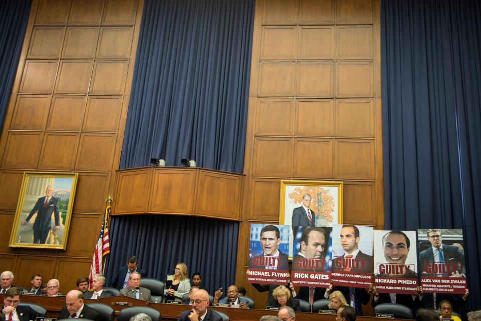 Attendees at a House committee hearing on July 12 hoist posters depicting five men who pleaded guilty to charges brought by Mueller.