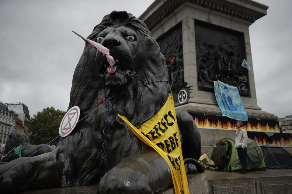 A lion statue is decorated by Extinction Rebellion climate change protesters in Trafalgar Square, London, Friday, Oct. 11, 2019. Some hundreds of climate change activists are in London during a fifth day of protests by the Extinction Rebellion movement to demand more urgent actions to counter global warming. (AP Photo/Matt Dunham)