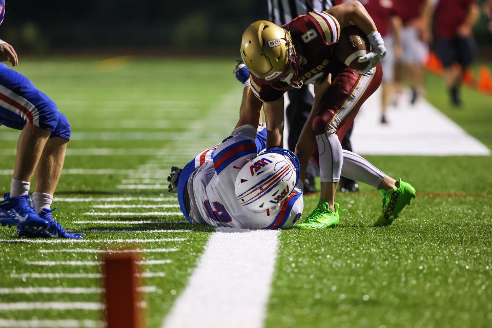 Winnacunnet's Mason McDonald forces Portsmouth's Angus Moss out of bounds in the first half of Friday's Division I football game.