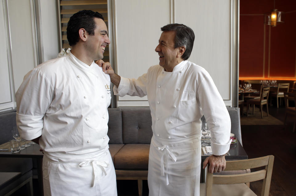 Chef Daniel Boulud, right, laughs with executive chef Jason Pringle, left, before hosting an exclusive lunch and book signing during the South Beach Wine and Food Festival at the db Bistro Moderne restaurant, Saturday, Feb. 22, 2014, in Miami. Boulud has an international food empire that includes more than a dozen restaurants and nearly as many cookbooks. (AP Photo/Lynne Sladky)