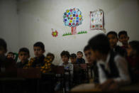 Syrian young boys attend a school class in an orphanage refugee camp for displaced people run by the Turkish Red Crescent in Sarmada district, on the outskirts north of Idlib, Syria, Friday, Nov. 26, 2021. Row upon row of tents, brick homes and other structures with water tanks on top dot the town of Sarmada near the border with Turkey, making up a series of huge informal refugee camps. Women cook, children play, men go to work, pray and discuss politics. Most of the inhabitants are displaced from various bouts of violence in Syria's 10-year conflict. (AP Photo/Francisco Seco)