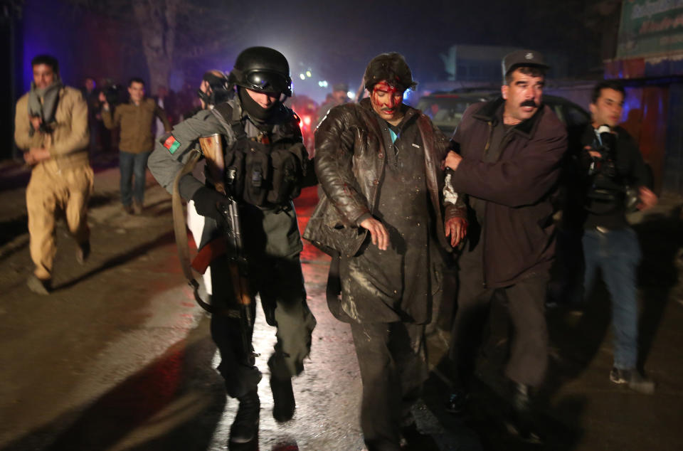 Afghan police forces assist an injured man at the site of an explosion in Kabul, Afghanistan, Friday, Jan. 17, 2014. Afghan police said a suicide bomber attacked a Kabul restaurant popular with foreigners, officials. (AP Photo/Massoud Hossaini)