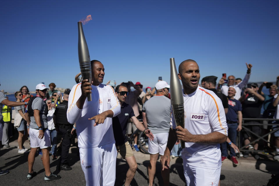 French torchbearers Tony Parker, right, and Gaetan Muller, left, participate in the first stage of the Olympic torch relay in Marseille, southern France, Thursday, May 9, 2024. Torchbearers are to carry the Olympic flame through the streets of France' s southern port city of Marseille, one day after it arrived on a majestic three-mast ship for the welcoming ceremony. (AP Photo/Thibault Camus)