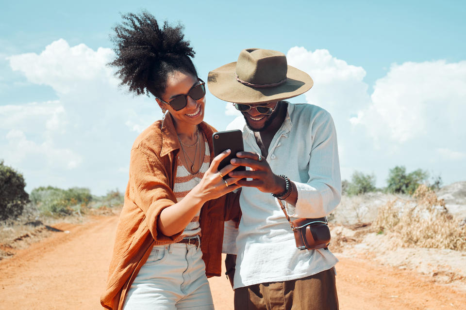 ouple with phone, travel and adventure, happy outdoors in outback Australia during summer vacation.