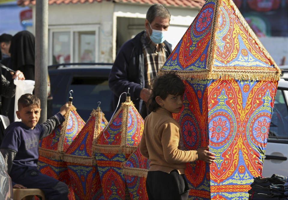 People shop for traditional lanterns for the holy month of Ramadan at the main market in Gaza City, April 11, 2021. Muslims are facing their second Ramadan in the shadow of the pandemic. Many Muslim majority countries have been hit by an intense new coronavirus wave. While some countries imposed new Ramadan restrictions, concern is high that the month’s rituals could stoke a further surge. (AP Photo/Adel Hana)