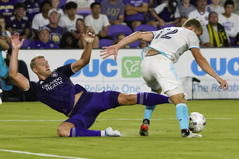 Orlando City's Robin Jansson, left, falls as he tries to keep New England Revolution's Justin Rennicks (12) from advancing the ball during the first half of an MLS soccer match Saturday, Aug. 6, 2022, in Orlando, Fla. (AP Photo/John Raoux)