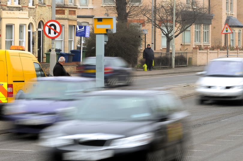 Cars drive past a yellow speed camera