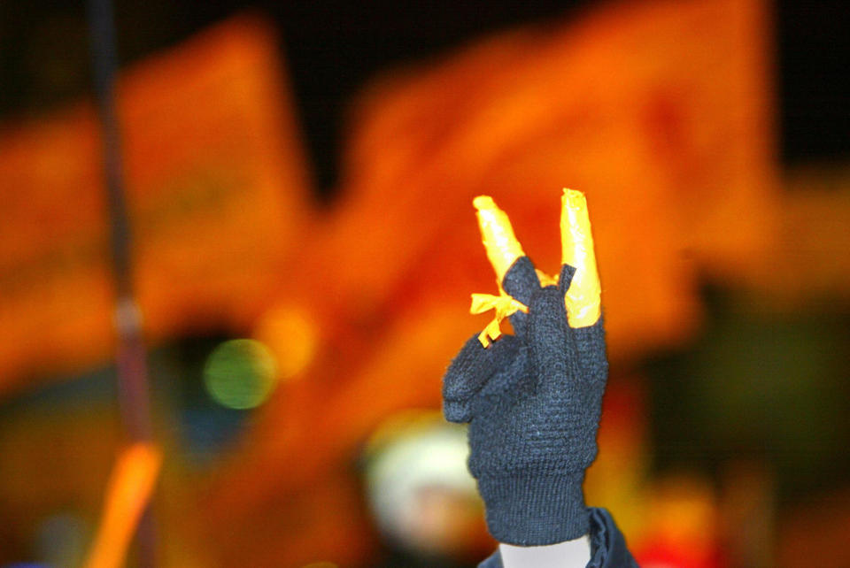 A supporter of Ukraine's opposition leader Viktor Yushchenko shows a V-sign during a mass rally marking the one-month anniversary of the "orange revolution" in Kiev's central Independence Square on Dec. 22, 2004. (Sergei Supinsky/AFP via Getty Images)