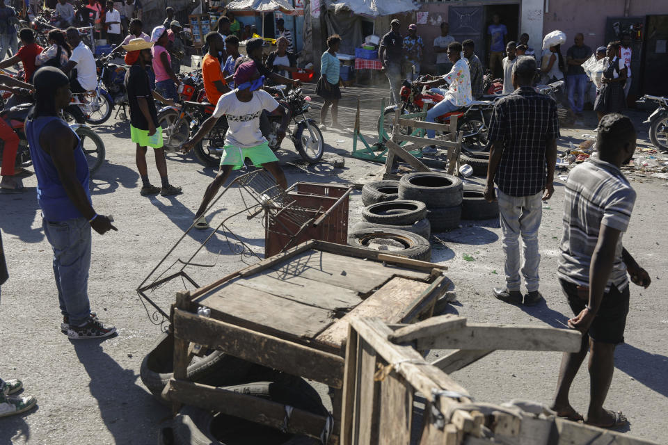 A protester threatens to throw a stone at motorcyclists crossing a barricade constructed by protesters to call attention to the country's insecurity and demanding the resignation of the prime minister, in Port-au-Prince, Haiti, Thursday, Jan. 18, 2024. (AP Photo/Odelyn Joseph)